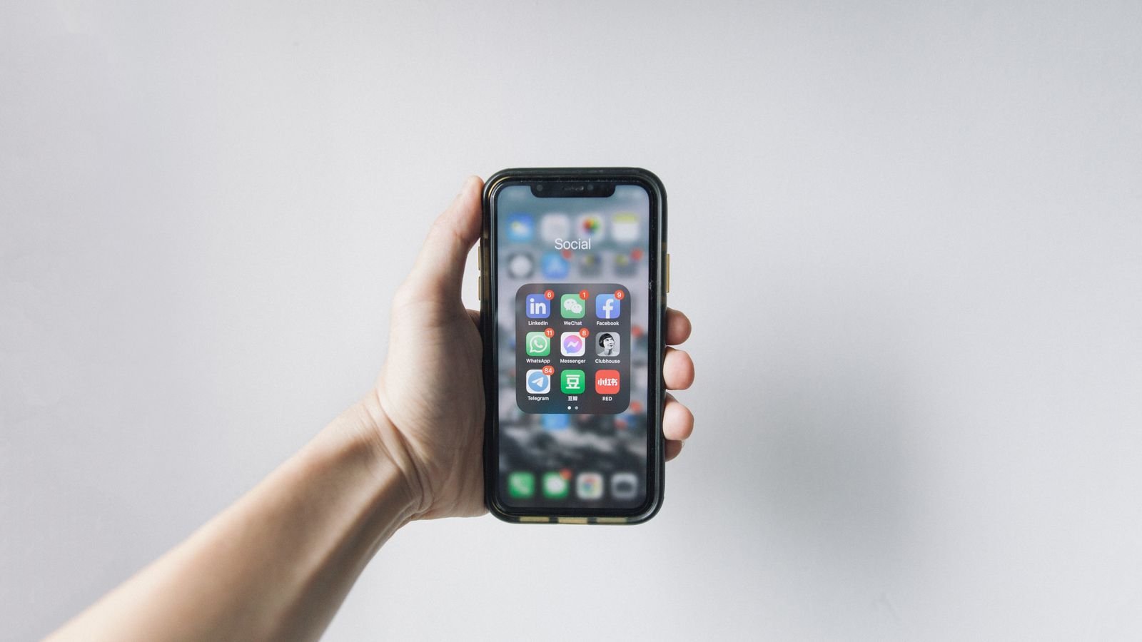 Hand holding a smartphone displaying app icons, representing big tech capital allocation between buybacks and AI investment