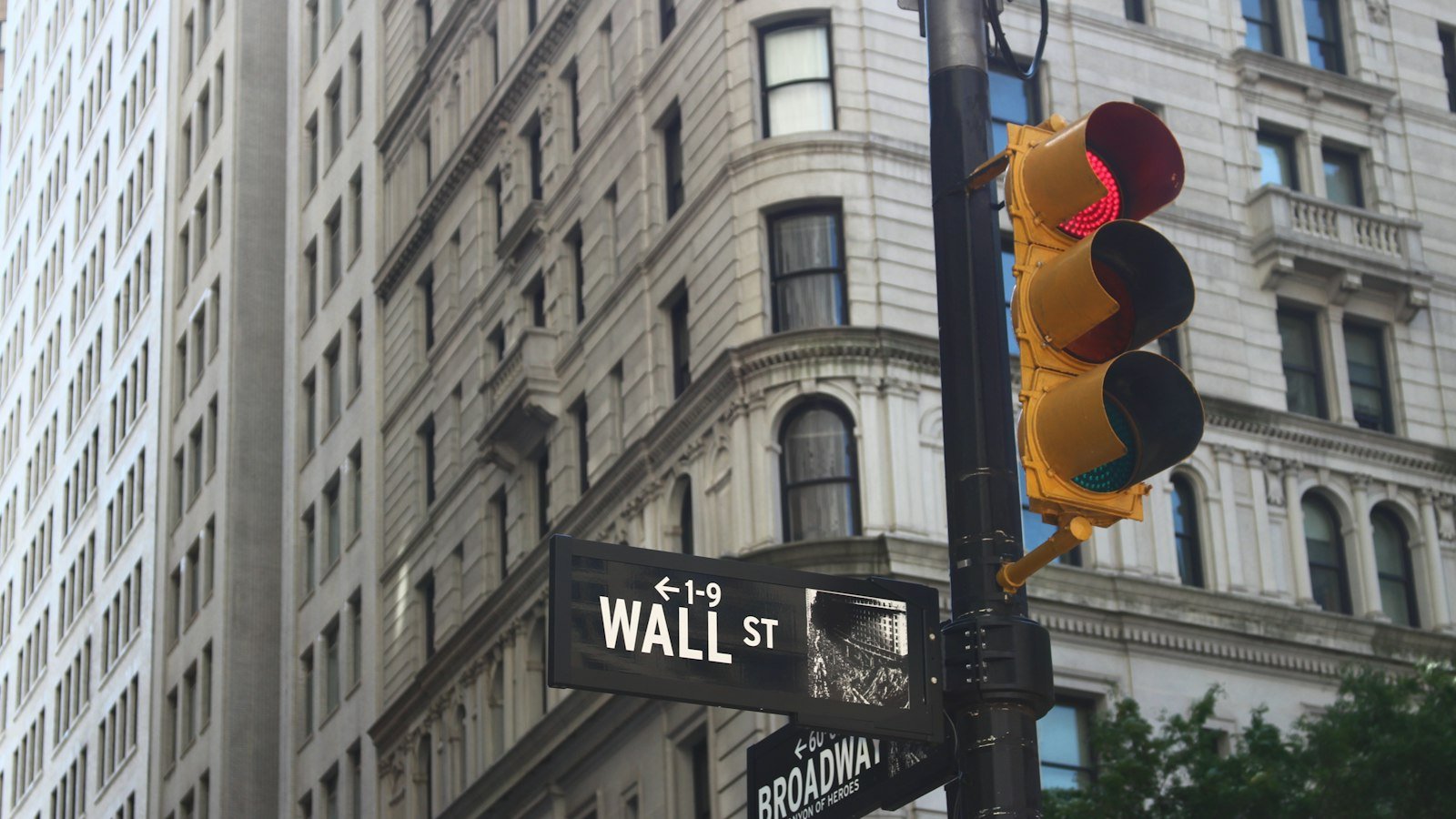 Wall Street and Broadway street signs above traffic lights in New York's financial district