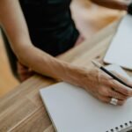 Person writing notes on paper during a weekly investment review