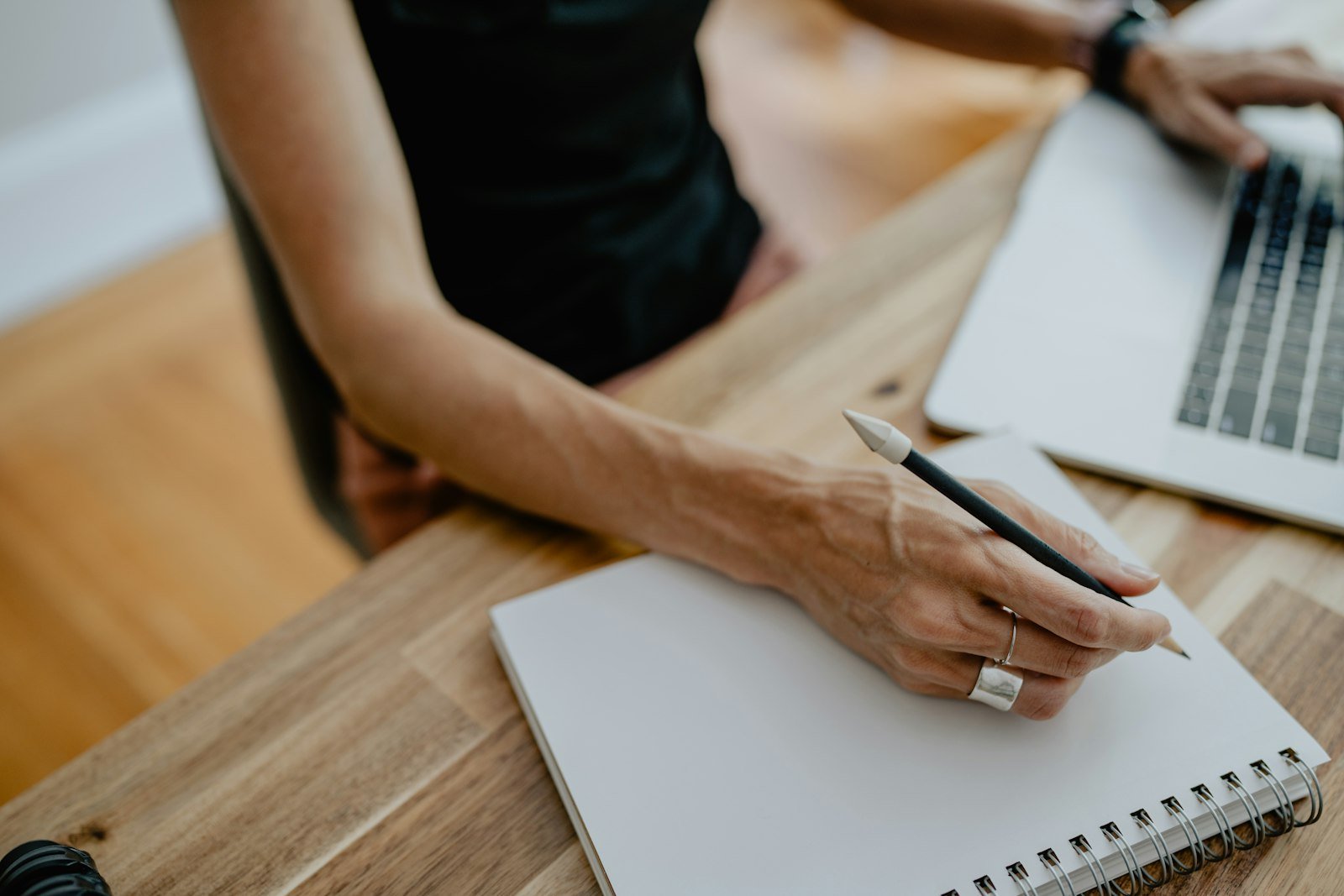 Person writing notes on paper during a weekly investment review